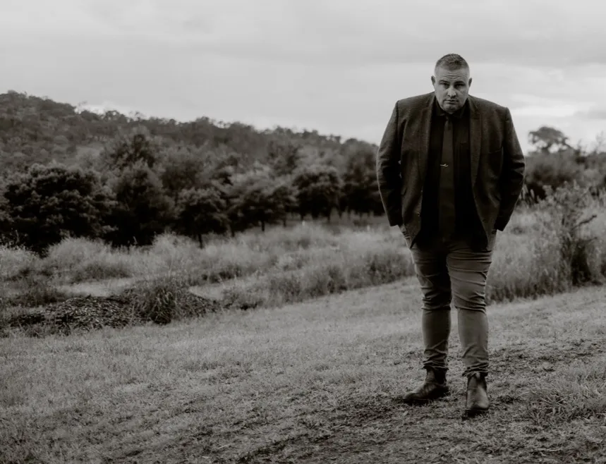 Black and white portrait of Josh Withers outdoors.