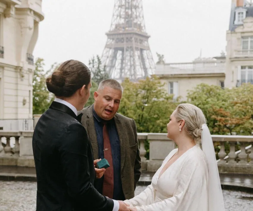 Josh conducting a wedding ceremony with a couple overlooking the Eiffel Tower in Paris.